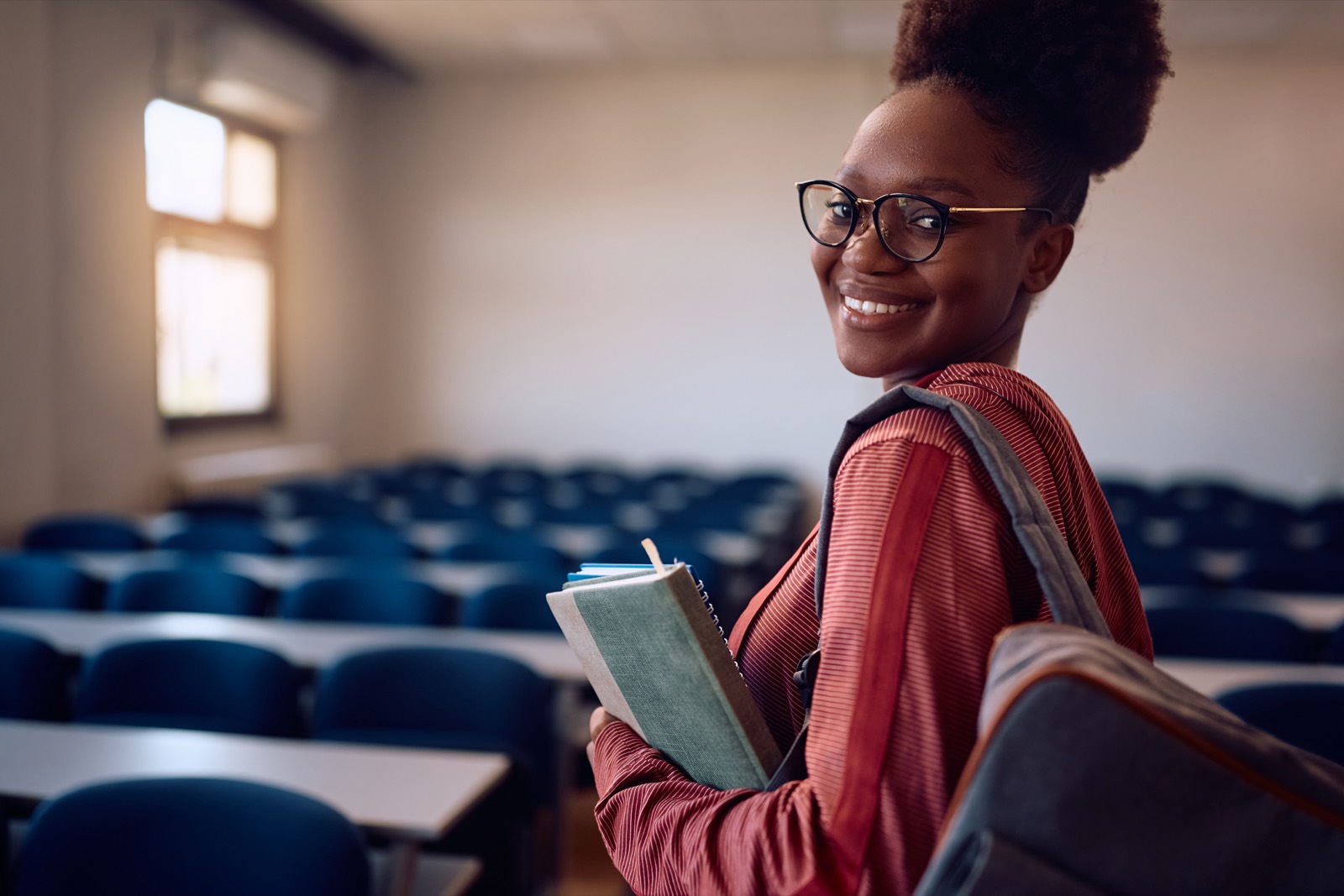 International student holding notebooks in a university lecture hall